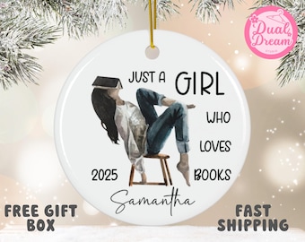 May include: White ceramic ornament with a watercolor illustration of a person sitting on a stool with a book on their head. Text reads "Just a Girl Who Loves Books" with the name "Samantha" and the year "2025".