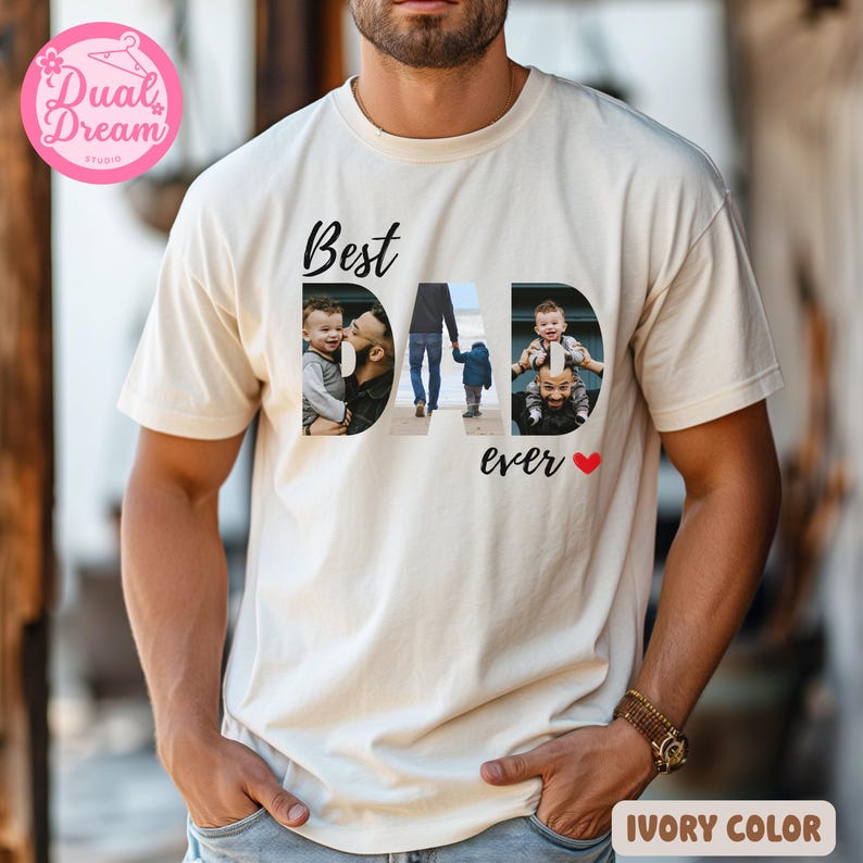May include: Ivory-coloured t-shirt with the words "Best DAD ever" in black script. The word "DAD" features three family photos. A small red heart is next to the word "ever". The shirt is a neutral colour.