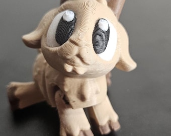 Könnte beinhalten: Eine hellbraune, 3D-gedruckte Figur einer Cartoon-Ziege mit großen, ovalen Augen. Die Ziege hat kleine Hörner, einen lächelnden Mund und ist auf allen Vieren positioniert. Die Augen sind weiß mit schwarzen Pupillen. Die Figur besteht aus geschichtetem Kunststoff.