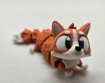 Könnte beinhalten: Ein 3D-gedrucktes, bewegliches Fuchspielzeug in Orange, Weiß und Schwarz. Der Fuchs hat große Augen, eine schwarze Nase und eine weiße Brust. Der segmentierte Körper ermöglicht eine flexible Pose. Der Schwanz ist weiß.