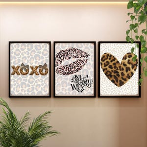 Op de afbeelding: Drie ingelijste wandkunstwerken met zwarte frames. De kunst toont luipaardprintontwerpen, waaronder XOXO-letters, een paar lippen en een hart. De tekst "WE ARE ALL WONDERFUL" is ook opgenomen.