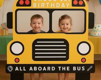 May include: A yellow school bus photo prop with the text "JACOB 1ST BIRTHDAY" at the top and "ALL ABOARD THE BUS" at the bottom. Two children are visible through the bus windows, smiling. The prop has black wheels and details.