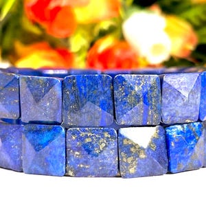 May include: A double-strand bracelet made of square-shaped lapis lazuli beads. The beads are a deep blue colour with gold flecks.