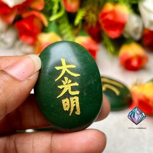 May include: A green oval-shaped stone with gold Chinese characters that read "大光明" (Da Guang Ming) which translates to "Great Light" or "Great Illumination".