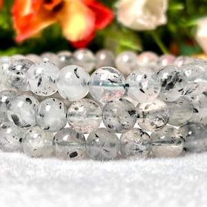 Peut inclure: Un bracelet composé de perles de quartz clair avec des inclusions noires. Les perles sont rondes et ont une finition lisse et polie.