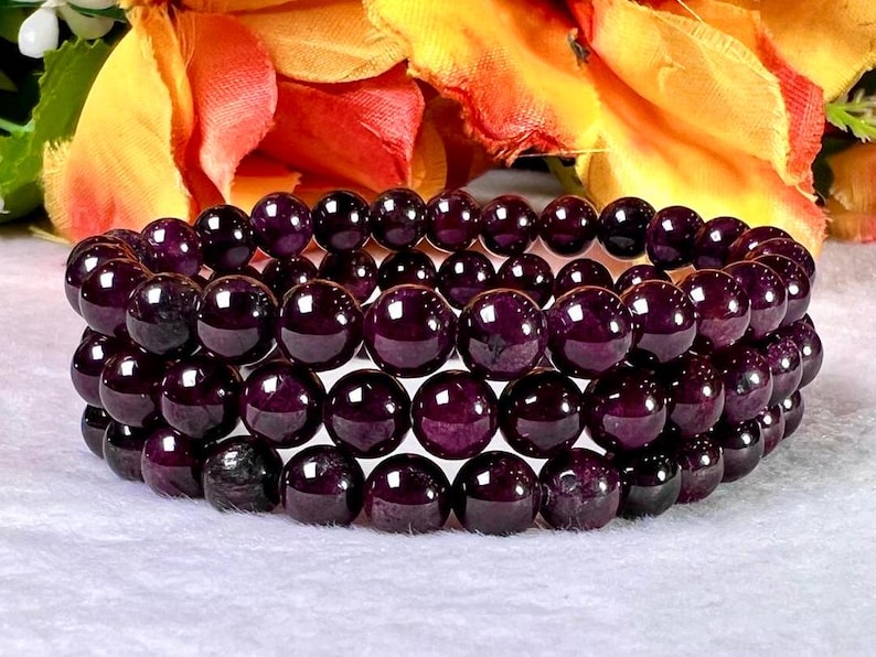 May include: A stack of three purple gemstone bracelets with round beads. The bracelets are made of natural stones and are perfect for layering.