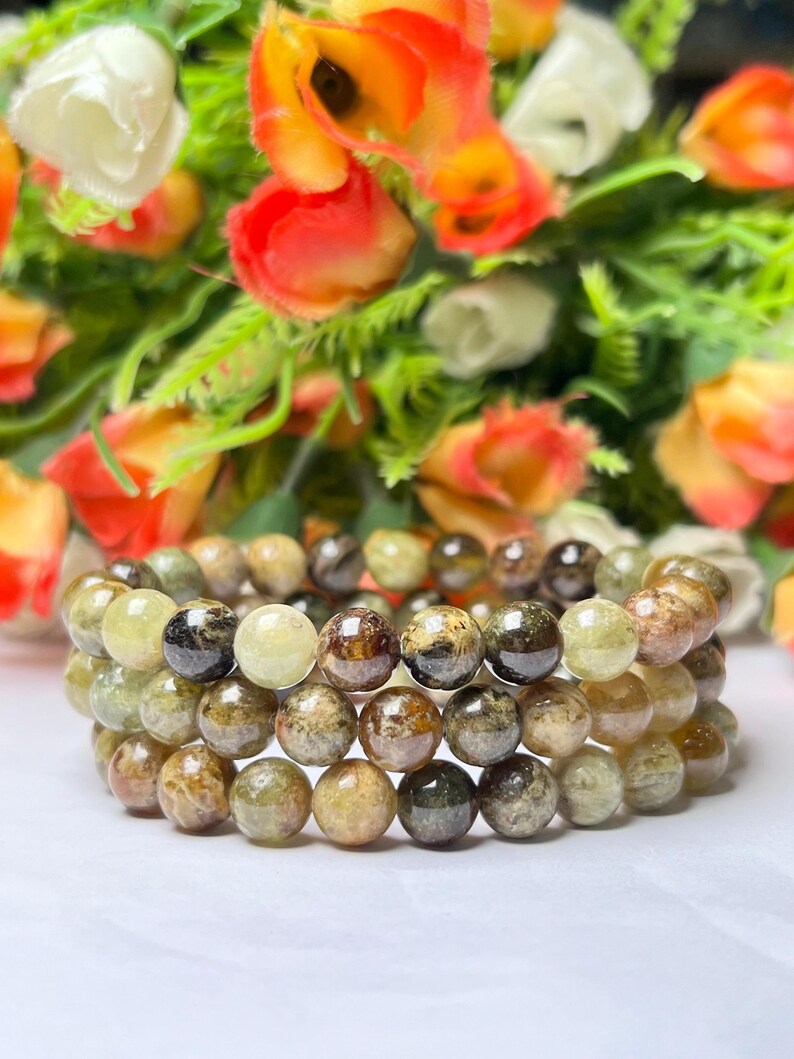 May include: Three stacked bracelets made of green and brown gemstone beads. The beads are round and have a speckled appearance.