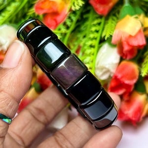 Peut inclure: Un bracelet en pierres précieuses noires et irisées avec des perles de forme carrée. Le bracelet est composé de plusieurs couleurs de noir, vert et violet.