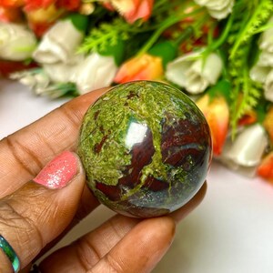 May include: Green and red jasper sphere, polished and smooth, with a swirling pattern of green, red, and brown. The sphere is about the size of a golf ball.