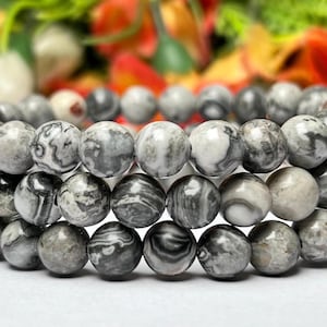 May include: Three stacked bracelets made of gray and white banded agate beads.