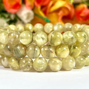 May include: A bracelet made of multiple strands of light green and yellow gemstone beads. The beads are round and have a translucent appearance.