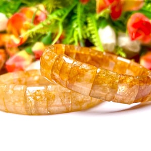 May include: Two golden brown bracelets made of square-shaped beads. The bracelets are made of a translucent material with a subtle shimmer.
