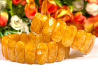 May include: Two yellow gemstone bracelets made of oval-shaped beads. The bracelets are stacked on top of each other.