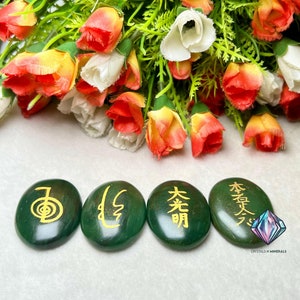 May include: Four green oval-shaped stones with gold Chinese characters inscribed on them. The stones are arranged in a row from left to right. The characters are "身", "心", "光明", and "本質".