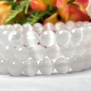 Könnte beinhalten: Ein weißes Edelstein-Armband mit runden Perlen. Das Armband besteht aus mehreren Perlenreihen.