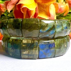 May include: Two stacked bracelets made of green labradorite gemstone beads. The beads are faceted and have a shimmering iridescent effect.
