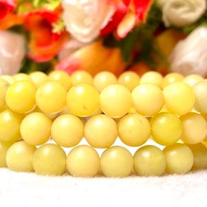 May include: A triple strand bracelet made of light yellow jade beads.