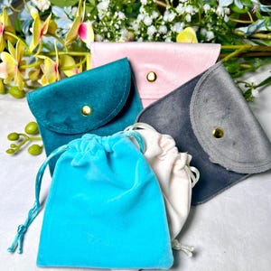 May include: Four velvet pouches in different colours: teal, pink, grey, and light blue. The pouches are made of soft, luxurious velvet and have a drawstring closure. They are perfect for storing small items like jewellery, coins, or other valuables.