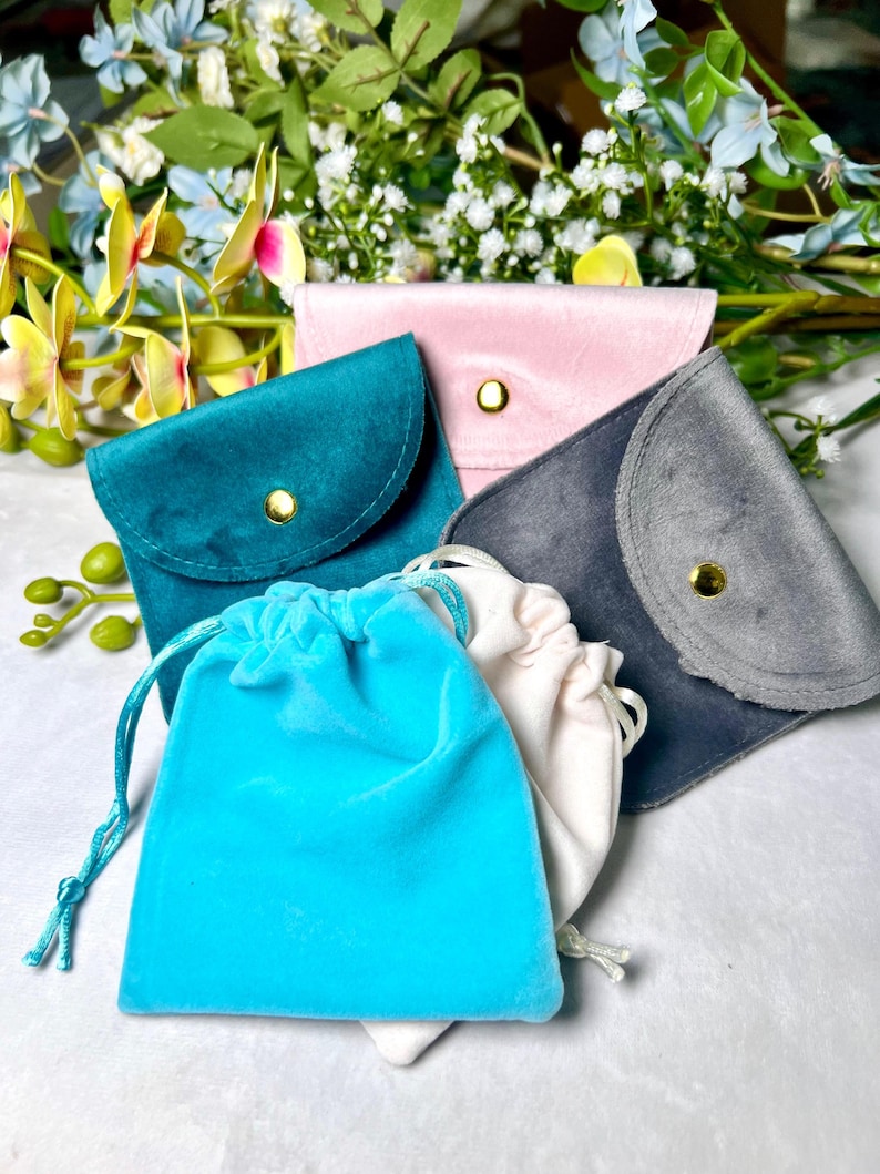 May include: Four velvet pouches in different colours: teal, pink, grey, and light blue. The pouches are made of soft, luxurious velvet and have a drawstring closure. They are perfect for storing small items like jewellery, coins, or other valuables.