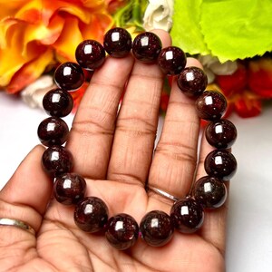 Peut inclure: Un bracelet en pierres précieuses de grenat rouge foncé avec des perles rondes. Le bracelet est fait de pierres naturelles et mesure environ 19 cm de long.