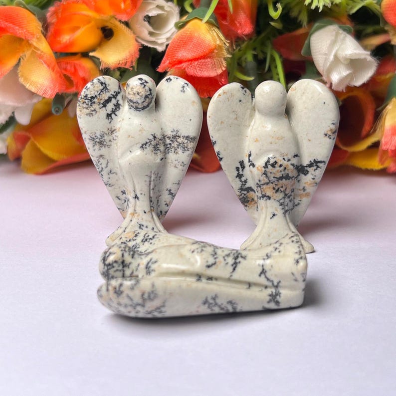 May include: Three white and black speckled stone angel figurines. The angels are carved in a standing pose with wings outstretched.