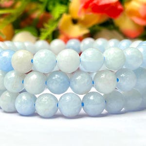 Peut inclure: Un bracelet à trois rangs composé de perles d'aigue-marine bleu clair. Les perles sont rondes et lisses, et elles sont enfilées sur un cordon élastique transparent.