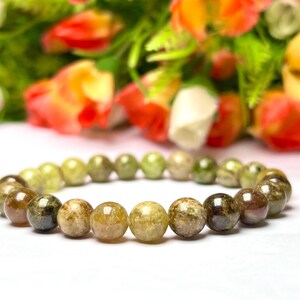 May include: A green and brown gemstone bracelet with round beads. The bracelet is made of natural stones and is a beautiful piece of jewelry.