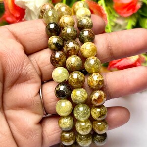May include: Three green and brown gemstone bracelets with round beads. The bracelets are stacked on top of each other.