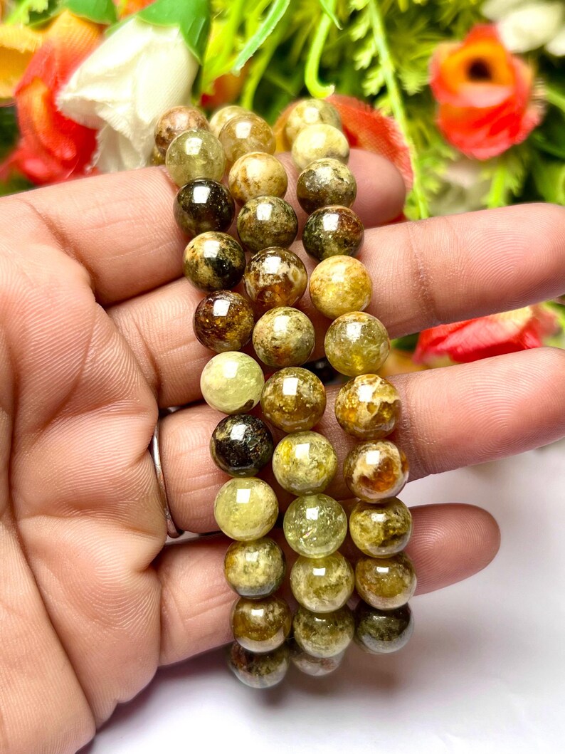 May include: Three green and brown gemstone bracelets with round beads. The bracelets are stacked on top of each other.