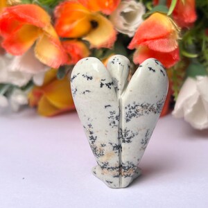May include: White and black speckled stone angel figurine. The angel is carved in a standing position with wings outstretched.