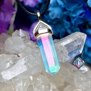 May include: A silver pendant with a clear iridescent crystal point, hanging from a black cord. The pendant is surrounded by white quartz crystals.