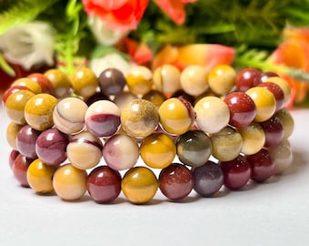 May include: A multi-strand bracelet made of round, multi-colored gemstone beads. The beads are a mix of yellow, red, and white.