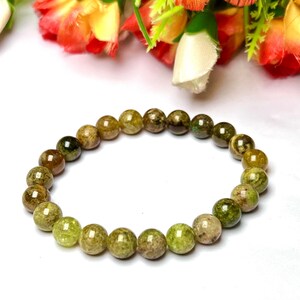 May include: A green and brown gemstone bracelet with round beads. The bracelet is made of natural stones and is a beautiful piece of jewelry.