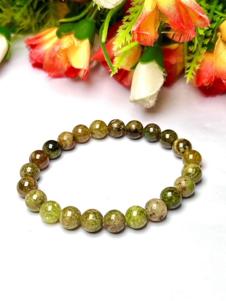 May include: A green and brown gemstone bracelet with round beads. The bracelet is made of natural stones and is a beautiful piece of jewelry.