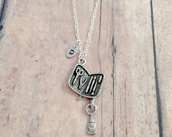 May include: Silver necklace with a charm that looks like an open nail polish kit with tools inside. The charm is attached to a small bottle charm that says "Nail Polish". The necklace has a silver initial charm with the letter "D" on it.