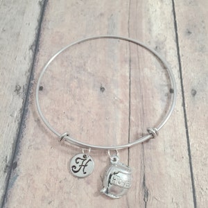 May include: Silver bangle bracelet with a charm of a honey pot and a charm with the letter H.