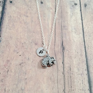 May include: A silver necklace with a small, silver charm of a wombat and a silver initial charm with the letter "P".