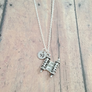 May include: Silver necklace with a silver Torah scroll charm and a silver initial charm with the letter "W".