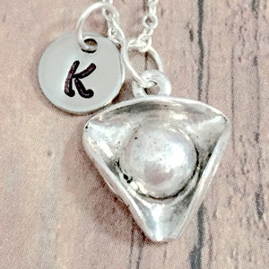 May include: Silver necklace with a silver pirate hat charm and a silver disc charm with the letter K.