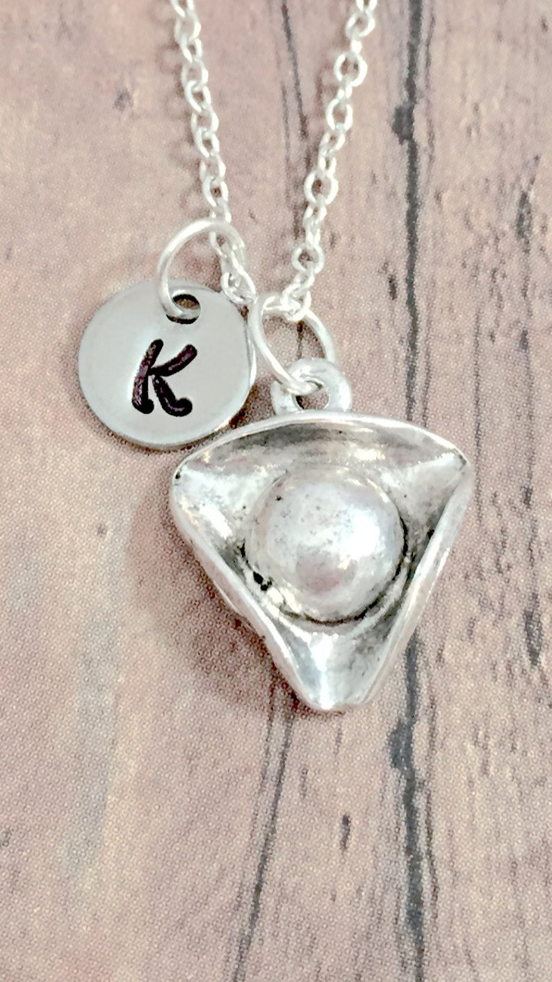 May include: Silver necklace with a silver pirate hat charm and a silver disc charm with the letter K.
