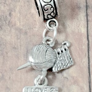 May include: Silver charm with a ball of yarn, crochet hook, and a sign that reads "I Love 2 Crochet".