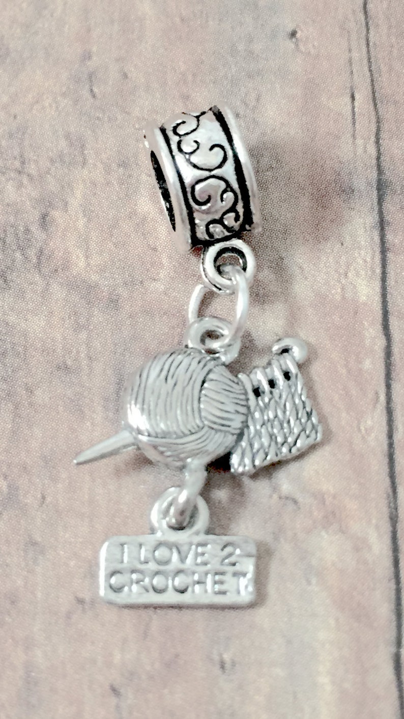 May include: Silver charm with a ball of yarn, crochet hook, and a sign that reads "I Love 2 Crochet".