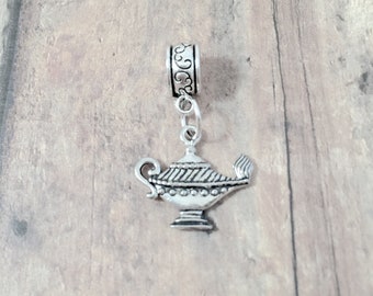 May include: A silver charm in the shape of an oil lamp with a decorative scroll design at the top.