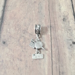 May include: Silver charm with a yarn ball, knitting needles, and a tag that says "C.S."