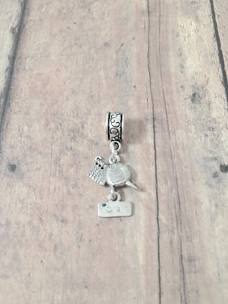 May include: Silver charm with a yarn ball, knitting needles, and a tag that says "C.S."