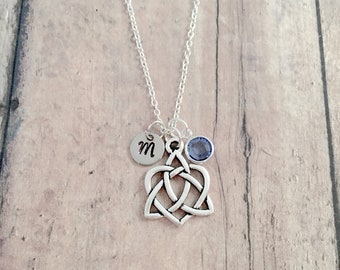 May include: Silver Celtic knot necklace with a small charm with the letter "M" and a blue gemstone.