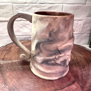 May include: A set of three ceramic mugs with a speckled, matte finish. The mugs are in shades of cream, light gray, and dark gray. Each mug has a simple, minimalist design, perfect for coffee or tea.