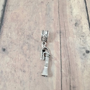 May include: Silver charm in the shape of a flashlight with a decorative silver ring.