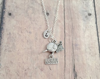 May include: Silver necklace with a charm of a yarn ball and crochet hook, a small sign that says "I love 2 crochet", and a letter "L" charm.