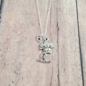 May include: Silver necklace with a charm of a chef's hat with the text "Le Chef" and a rolling pin. The necklace has a silver initial charm with the letter "K".